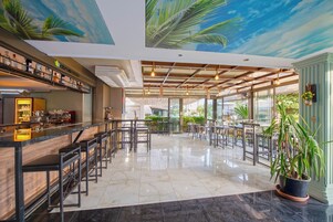 A spacious bar area with high stools and a counter, large windows, and a ceiling mural.