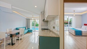 A modern living room with a dining area, kitchen, and a balcony with a pool. - Citrus Park Hotel (Konyaalti)