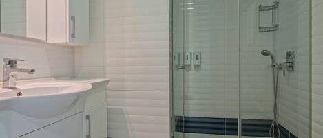 Een moderne badkamer met een douchecabine van glas, een wit wastafelmeubel en een toilet.