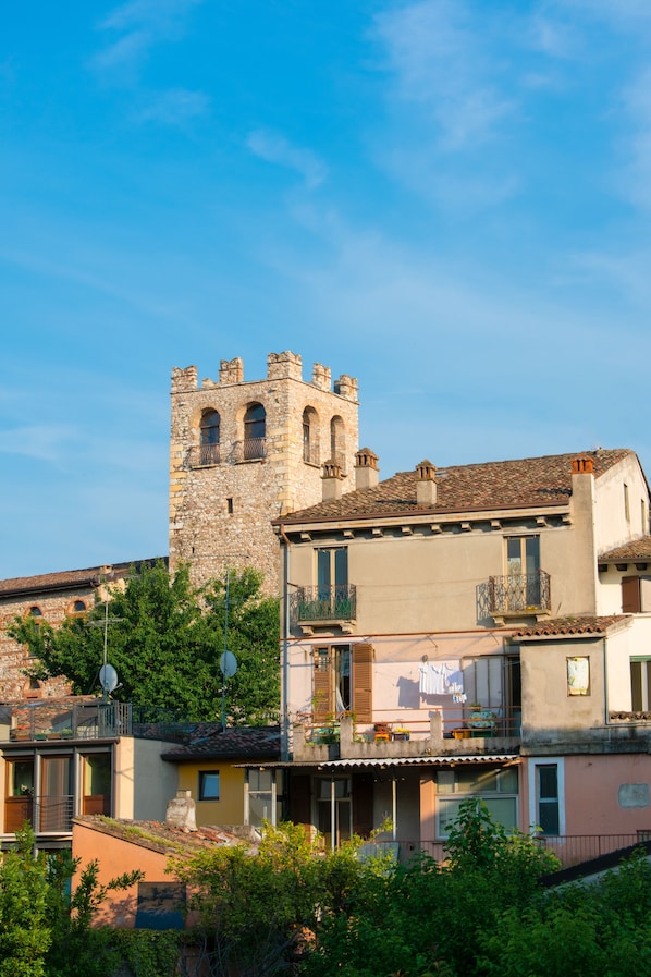 A historic stone tower with a balcony, surrounded by residential buildings with balconies and satellite dishes.