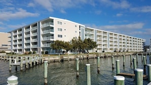 A waterfront hotel with multiple balconies, a dock area, and a clear sky. - Thunder Island 80b 2 Bedroom Condo by RedAwning (Ocean City)