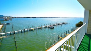 A view from a balcony overlooking a marina with docks extending into calm water, a clear sky, and distant buildings. - Thunder Island 80b 2 Bedroom Condo by RedAwning (Ocean City)