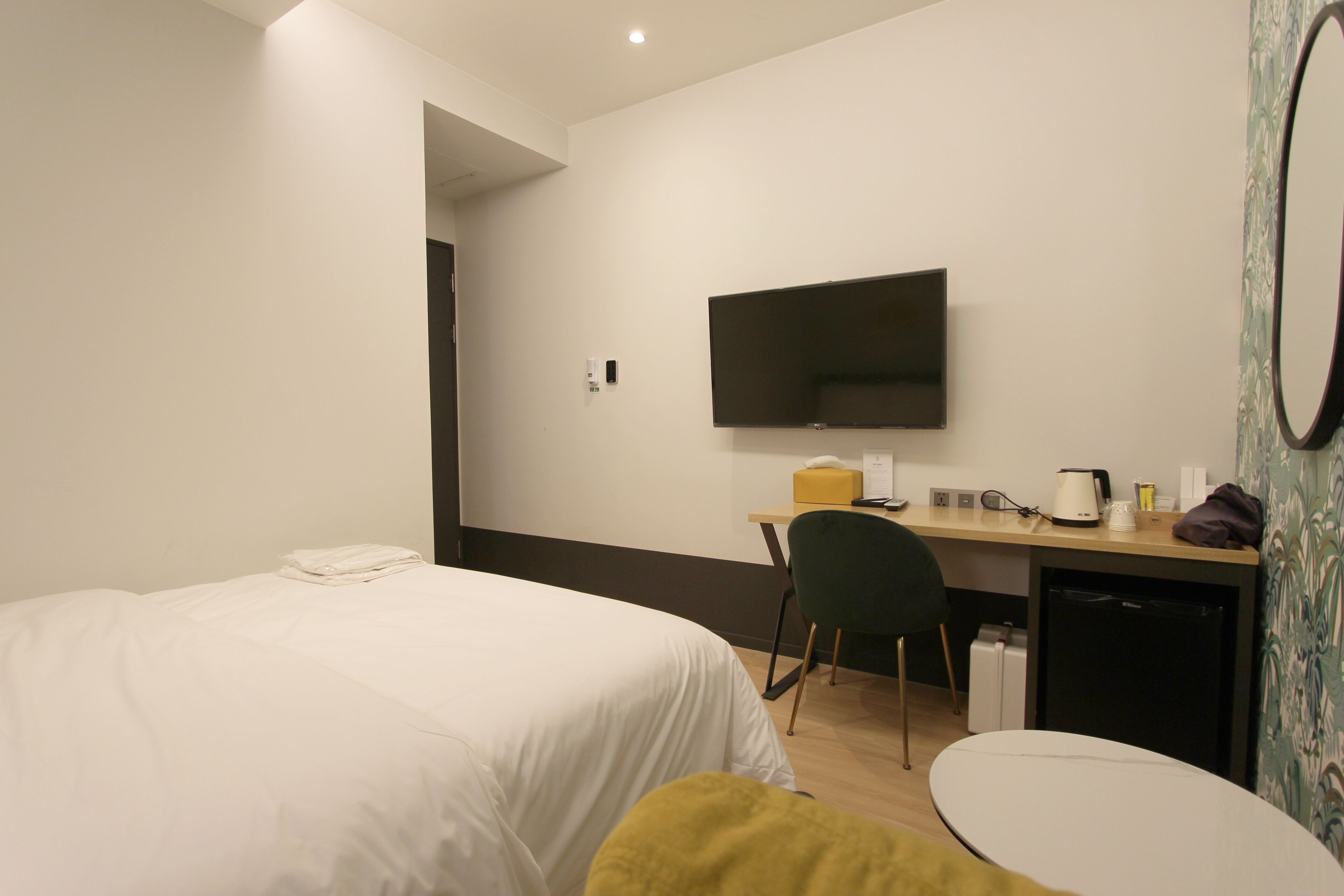 Ett hotellrum med en säng, ett skrivbord med en stol, en tv och ett litet bord.
