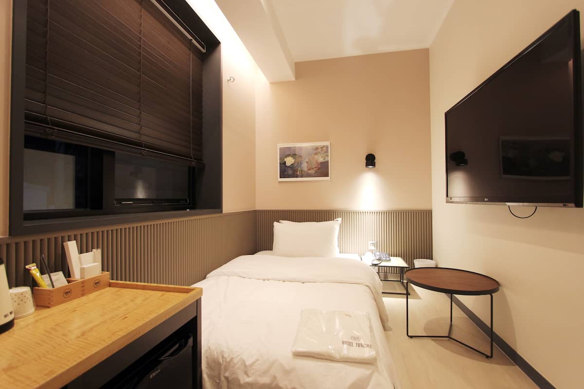 Una habitación de hotel con cama, mesita de noche y una pequeña mesa.