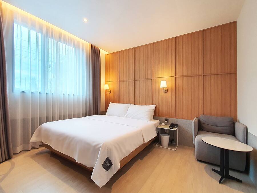 A hotel room with a large bed, a desk, a chair, and a small table.