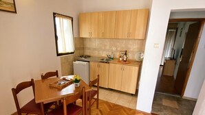 Uma cozinha compacta com armários de madeira, uma mesa de jantar com cadeiras e um chão com padrão herringbone.