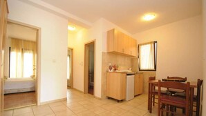 Uma cozinha compacta com armários de madeira, uma bancada pequena e uma área de refeições com mesa e cadeiras.