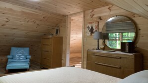 A cozy cabin room with a bed, dresser, and blue chair. - Muskegon River Cabin (Hersey)