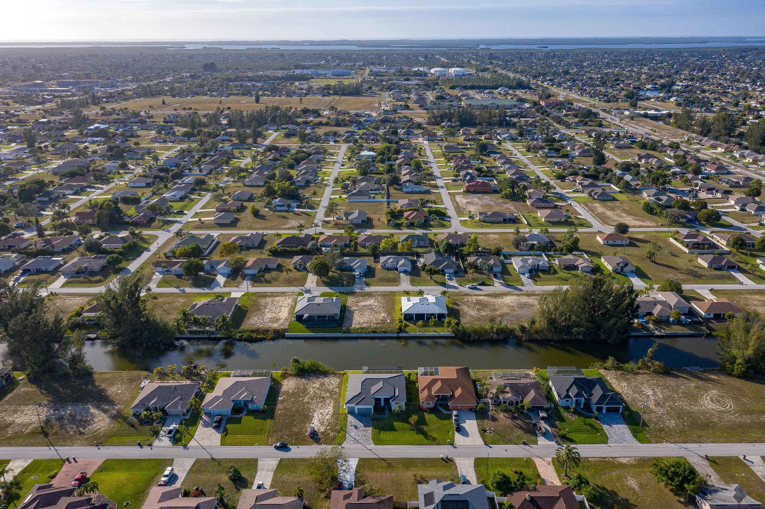 An aerial view of a residential area with houses, roads, and a canal.