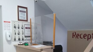 Zona de recepción con un mostrador, un certificado enmarco, una cámara de seguridad y un letrero que dice "Reception".