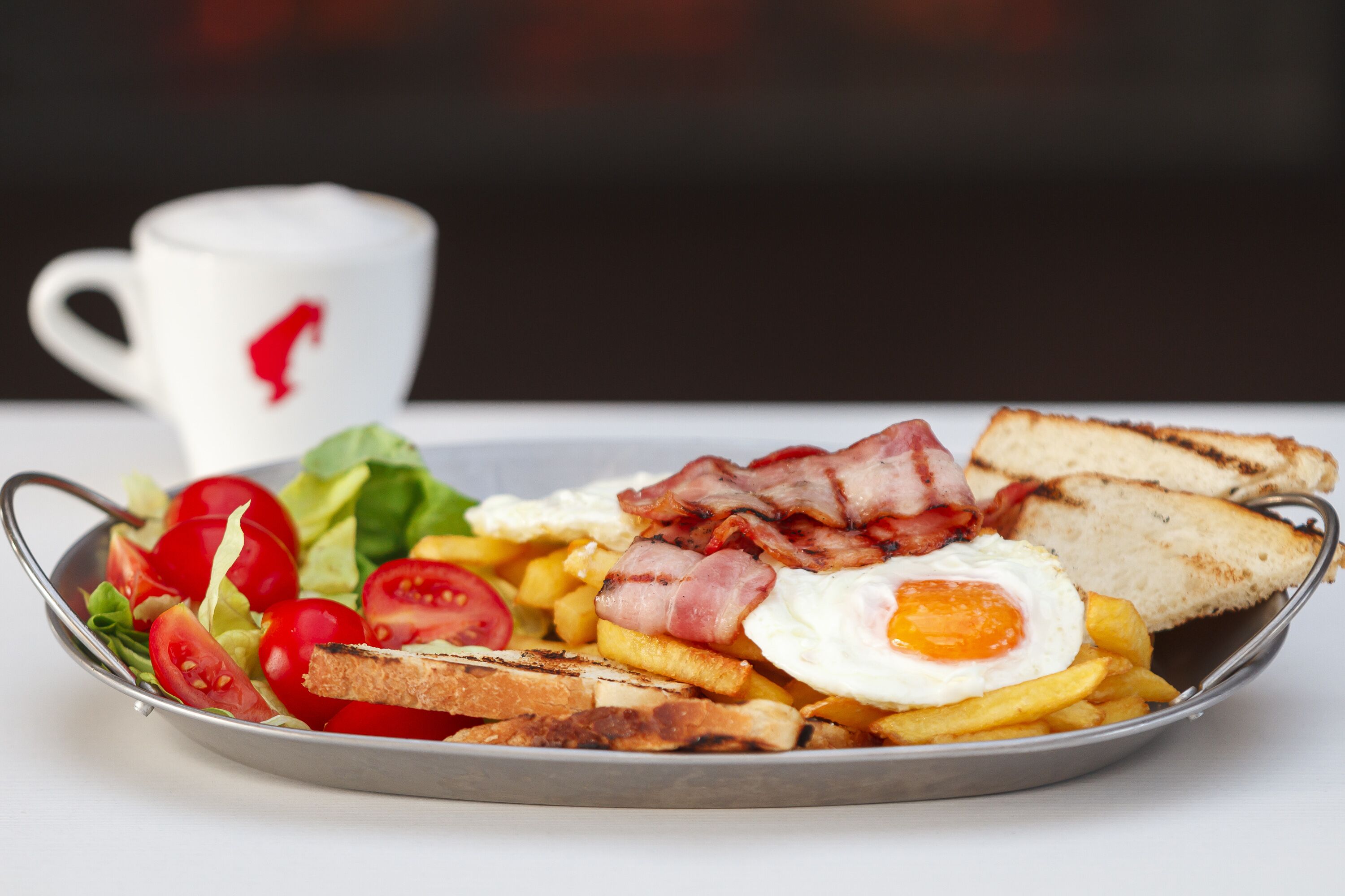 A breakfast plate with eggs, bacon, toast, and tomatoes.