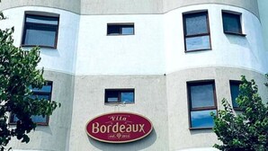 Un edificio con fachada curva, un letrero 'STAGE' en la parte superior y un letrero 'Vila Bordeaux' debajo.