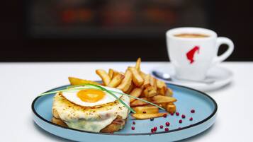Um prato com sanduíche, batatas fritas e uma xícara de café.