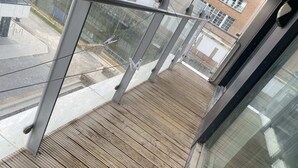 A wooden deck with metal railings and a glass balustrade. - Clean and modern Riverside Flat w/ Private Balcony (Norwich)