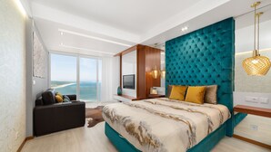 A modern bedroom with a large bed, a sofa, a TV, and a view of the ocean. - Stunning View Apartment - Adults Only (Nazaré)