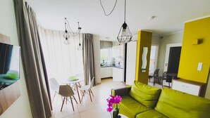 Una sala de estar moderna con un sofá verde, una mesa de centro blanca y un comedor con sillas y una mesa.