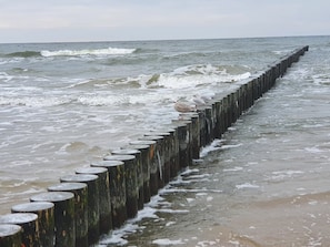 Una defensa marítima de madera con olas chocando contra ella.