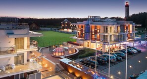 A modern hotel with multiple floors, outdoor seating areas, and a parking lot. - Kliff Apartamenty (Rewal)