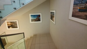 Una escalera con barandillas de vidrio y tres cuadros en la pared.
