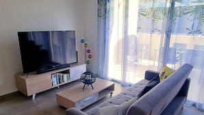 A living room with a sofa, a TV, a coffee table, and a window with curtains.