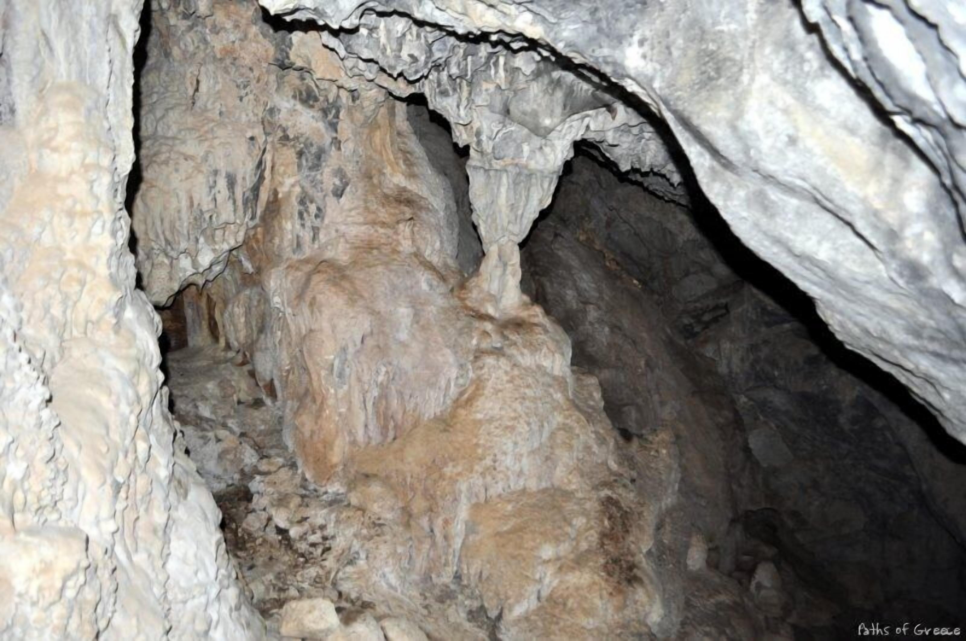 A cave interior with rugged rock formations and a narrow passageway.