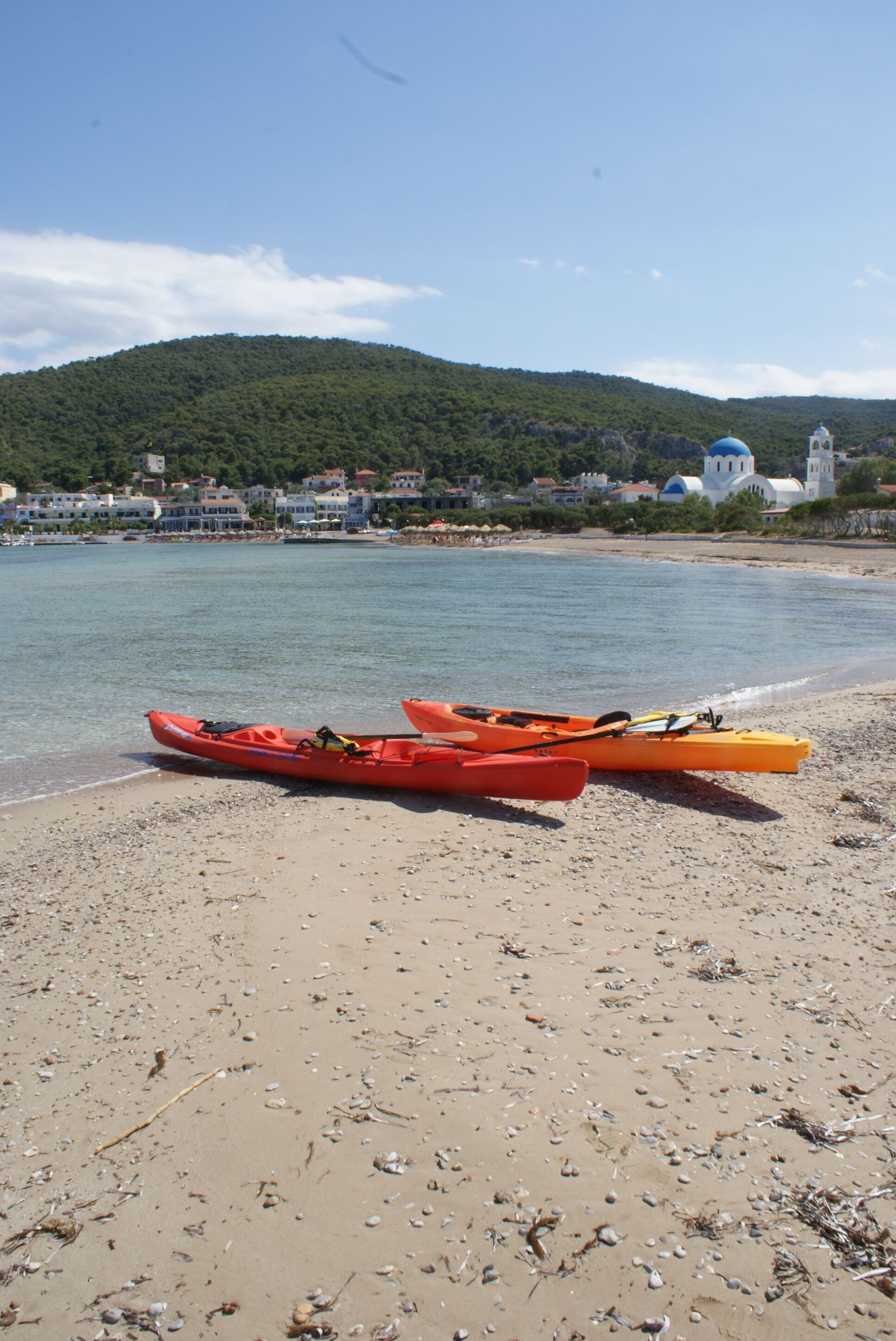 A beach with kayaks and a church in the background.