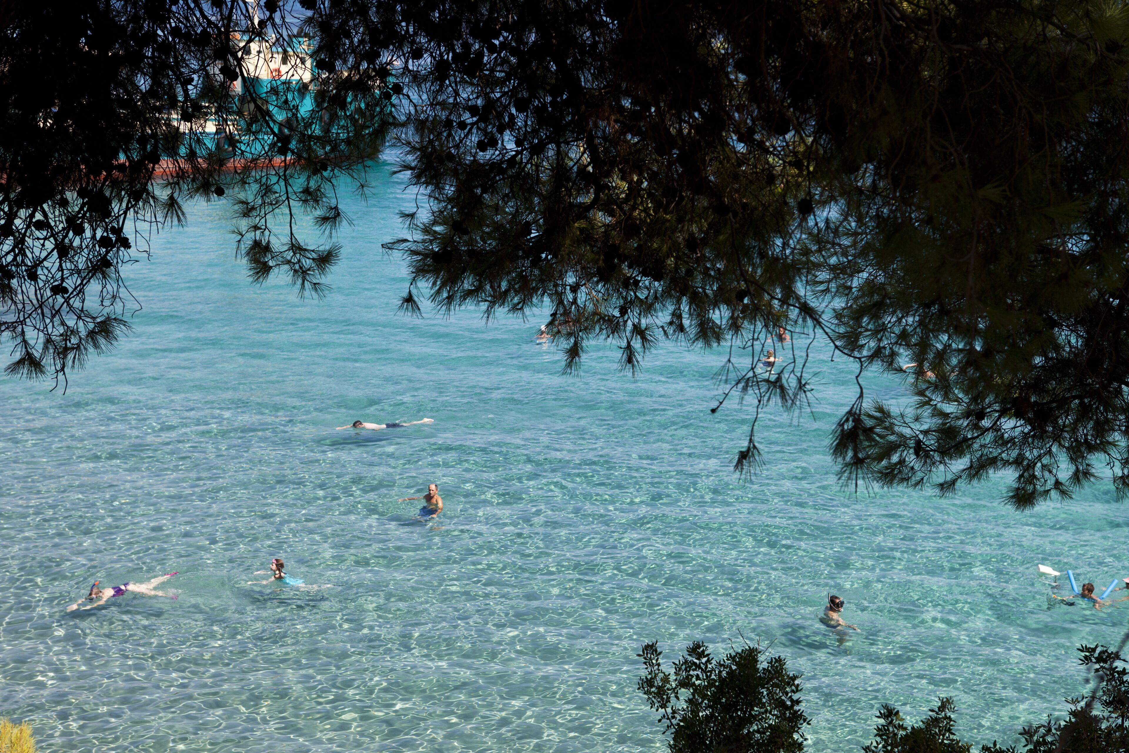 Una playa con gente nadando y practicando surf.