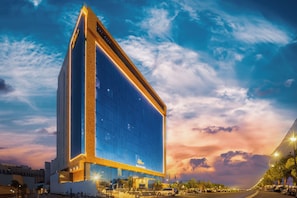 Un hotel alto con una fachada de vidrio destacada y un dise ño geométrico distintivo en la base.