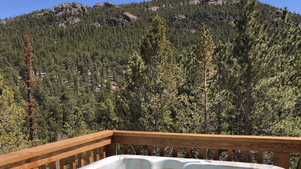 Een hottub op een houten terras met een bergachtig achtergrond.
