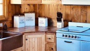 Een keuken met houten kastjes, een witte magnetron, een fornuis en bakken met de aanduiding 'Country Farm Flour', 'Koffie' en 'Suiker'.