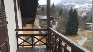 A wooden balcony with a view of a mountainous landscape.