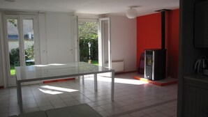 Une pièce spacieuse avec une grande table et des chaises, un téléviseur et un mur d’accent de couleur rouge.