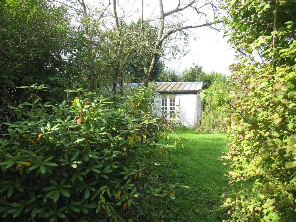 A white building with a metal roof, surrounded by dense greenery and trees.