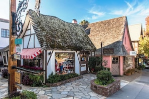A traditional building with a thatched roof, a shop with a striped awning, and a sign for 'Cottage Sweets.'