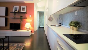 Une cuisine moderne avec des meubles blancs, un plan de travail noir et un revêtement mural en carreaux. On y trouve un évier, une cuisinière et un plan de travail agrémenté de deux plantes en pot.
