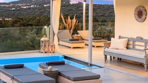 Un espace de détente extérieur moderne, doté d’une piscine, de sièges et offrant une vue sur la campagne.