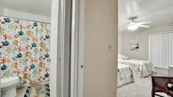 A bedroom with a bed, a ceiling fan, and a window with blinds.