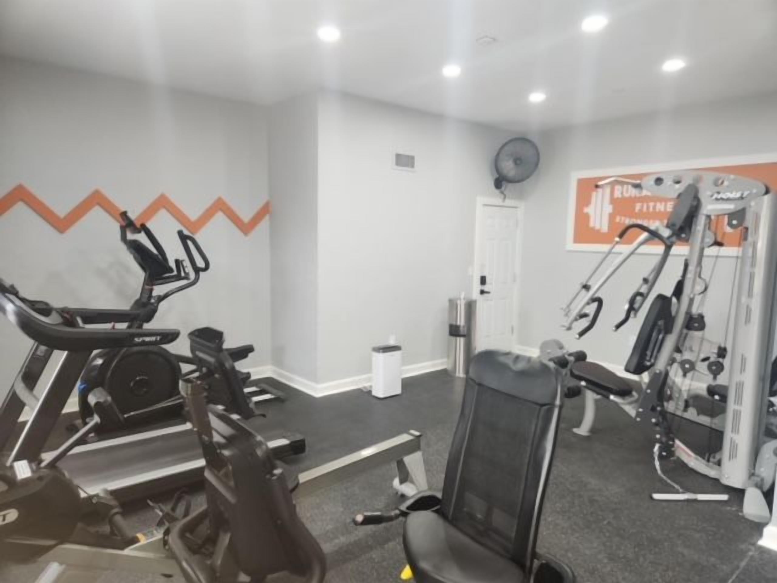A gym with a stationary bike, a weight bench, and a wall-mounted exercise machine.