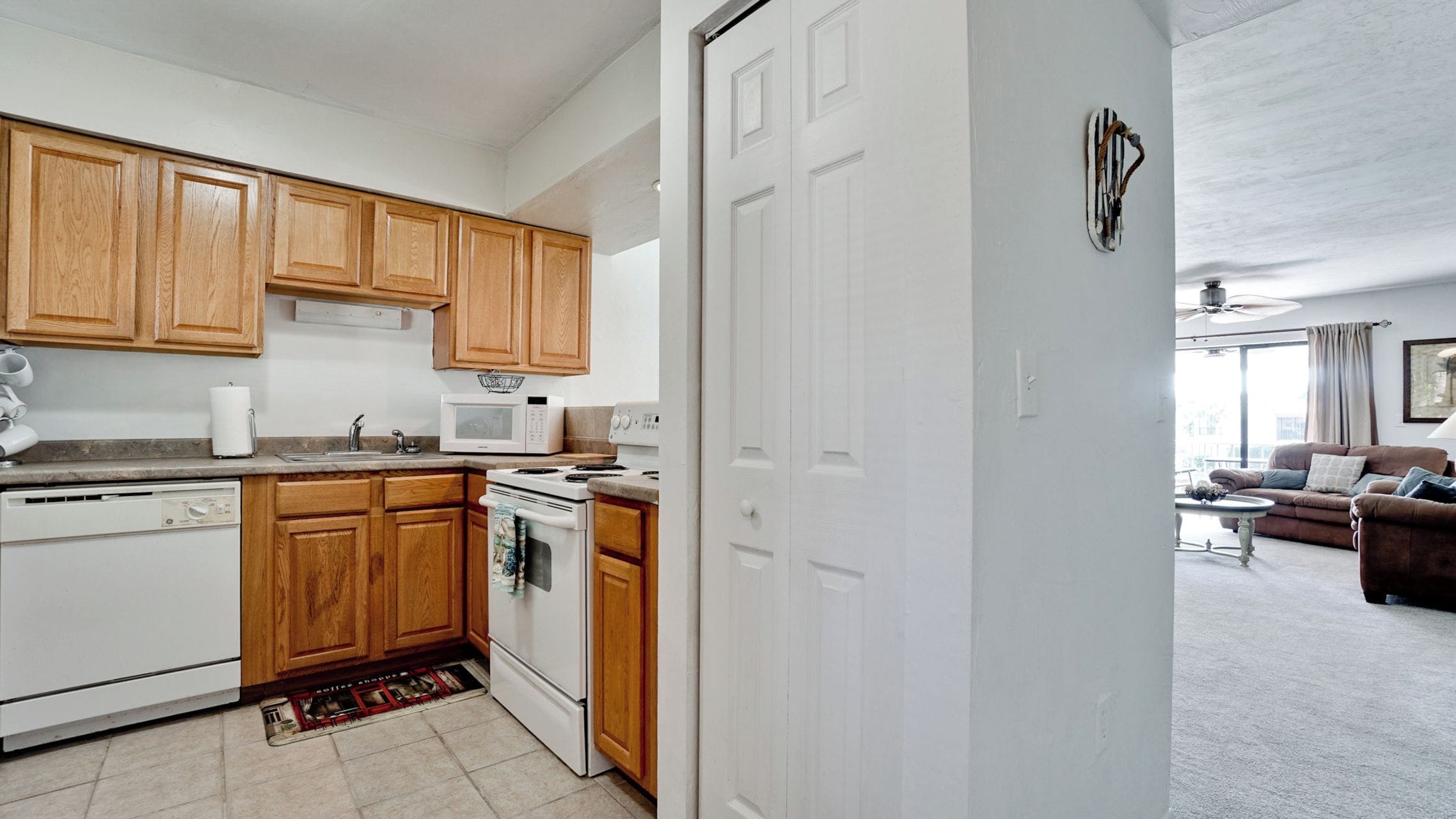A compact kitchen with wooden cabinets, a microwave, a stove, and a dishwasher.