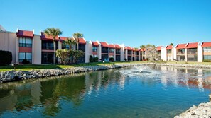 A hotel with multiple red-roofed buildings, a central water feature, and well-maintained landscaping. - Runaway Bay 213 (Bradenton Beach)