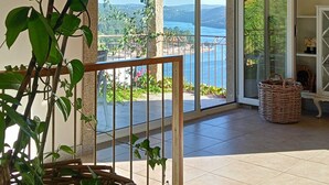 A room with a view of a body of water, a balcony with a wicker basket, and a large potted plant. - Holliday Villa - Casa do Sobreiro (Melres, Gondomar)