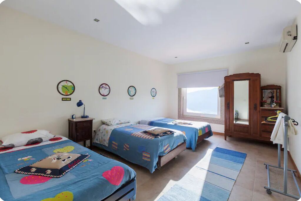 Un dormitorio con dos camas, un armario, un espejo y una ventana.