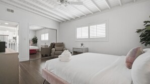 Een slaapkamer met een groot bed, een stoel, een nachtkastje en een spiegel.