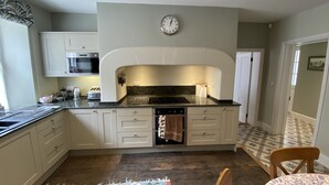 A kitchen with a built-in oven, a clock on the wall, and a patterned rug on the floor. - Charming 3 bedroom house in the heart of Ludlow (Ludlow)