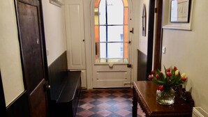 A hallway with a checkered floor, a bench, a table with a vase of flowers, and a door with a frosted glass window. - Charming 3 bedroom house in the heart of Ludlow (Ludlow)