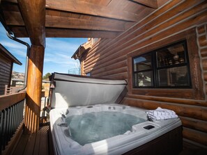 Ein Whirlpool in einer Blockhütte mit einer Holzterrasse und einem Fenster.