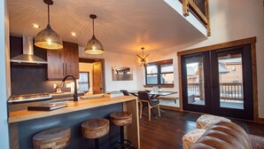 Una cocina moderna con una isla central, taburetes de madera y lámparas colgantes.