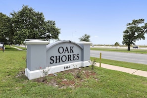 Discover Oak Shores, a serene residential community with a prominent sign and lush green surroundings.