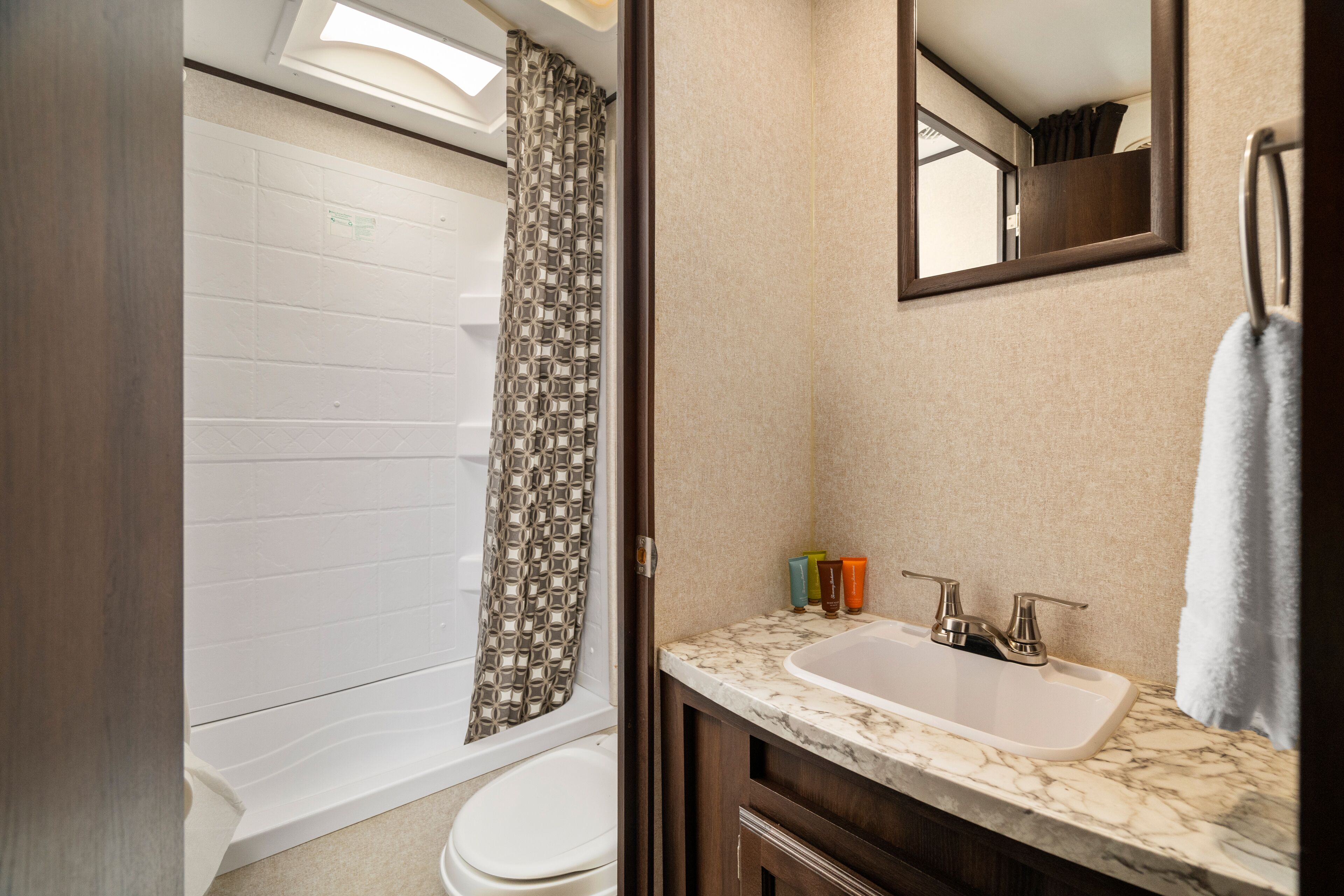 Une salle de bain avec douche, toilettes et lavabo, avec un miroir au-dessus.