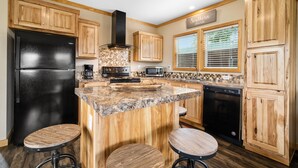 A kitchen with wooden cabinets, a black refrigerator, a microwave, a stove, and a dishwasher. There is a sign that says "Southern charm".